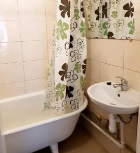 a bathroom with a sink and a shower curtain at Bright spacious apartment with street parking in Rīga