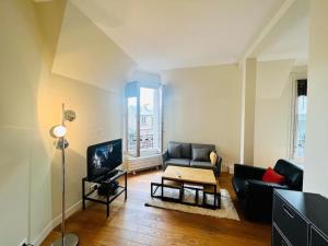 a living room with a couch and a tv at Suffren Studio in Paris