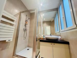 uma casa de banho com um lavatório e um chuveiro com um espelho. em Suffren Studio em Paris
