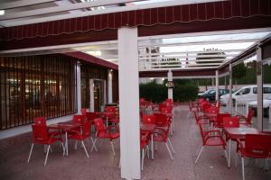 Hostal Santa Barbara في Socuéllamos: مطعم فيه كراسي حمراء وطاولات على رصيف