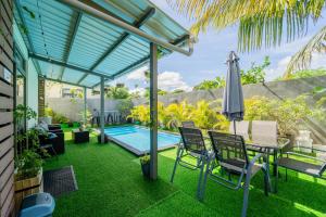 um pátio com uma mesa, um guarda-sol e uma piscina em Keenoo Villa - An elegant villa in a calm area em Pamplemousses Village