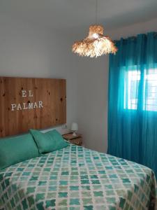 1 dormitorio con 1 cama con cortinas azules y lámpara de araña en CasaMaria 50 metros de la playa, en El Palmar