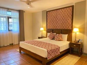 a bedroom with a bed with a large headboard at Tamarind Tree Garden Resort - Katunayake in Negombo