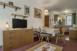 a living room with a table and a television on a cabinet at Chalet Pradat in Arabba