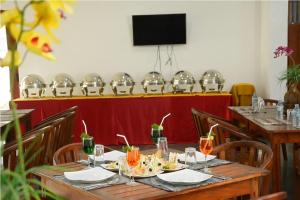 a dining room with tables and chairs and a television at Trinco Rest House in Trincomalee