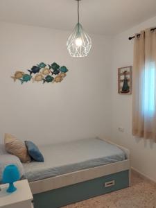 1 dormitorio con 1 cama y luz colgante en CasaMaria 50 metros de la playa, en El Palmar