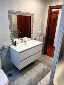 ein Badezimmer mit einem weißen Waschbecken und einem Spiegel in der Unterkunft Rodeira in Cangas