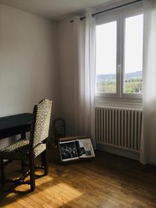 a room with a table and a chair and two windows at Les Remparts in Châteauneuf-du-Faou