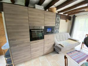 a living room with a large wooden cabinet with a tv at Au Chêne Gauthier in Pouillé +4 photos