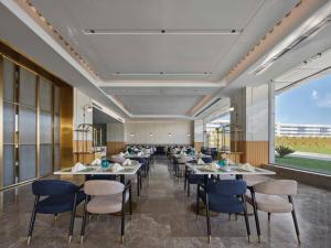 um restaurante com mesas e cadeiras e janelas grandes em Hilton Garden Inn Kunming Dianchi em Kunming