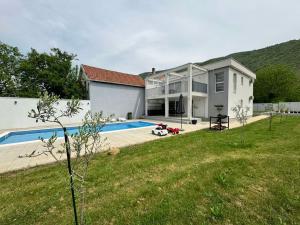 a house with a swimming pool in front of a yard at Villa Aqua in Mostar