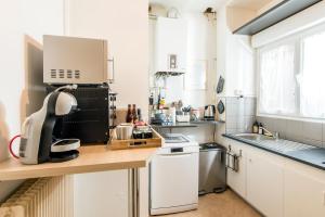 a small kitchen with white cabinets and a counter top at Suites Mana - Bleu Pacifique - Vue sur Place Ducale avec Parking privé inclus in Charleville-Mézières