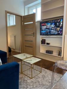 - un salon avec deux tables et une télévision à écran plat dans l'établissement Apartament Glamour, à Toruń