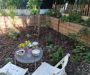 un jardín con una mesa y 2 sillas y una mesa con flores en Chambre Cassis en Arlés