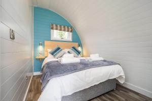 een slaapkamer met een bed met een blauwe muur bij Dilham Hall Retreats in Dilham
