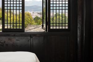 a bedroom with a window with a view of a city at 丽江山之名·音糖·大美华宿（束河古镇店） in Lijiang