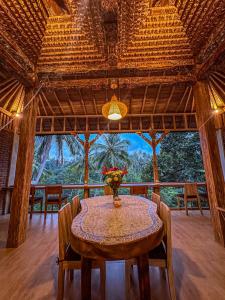 a dining room with a table with a vase of flowers on it at Made Punias Jungle Paradise in Ubud