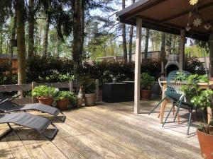 eine Terrasse mit Stühlen, Tischen und Topfpflanzen in der Unterkunft Chalet Luxe in Zutendaal