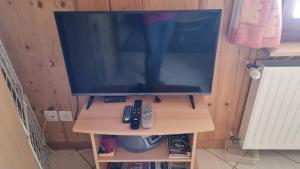 a television on a stand with two remote controls at Studio à la ferme in La Brévine