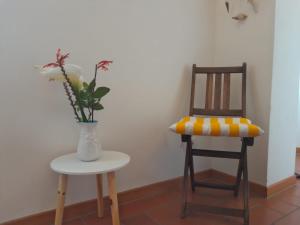 un jarrón de flores sentado en una mesa junto a una silla en Voglia di mare, en Capraia