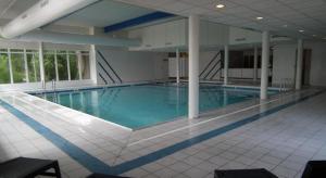 een groot zwembad met blauw water in een gebouw bij Appartement De Kompaan, Resort Amelander Kaap in Hollum