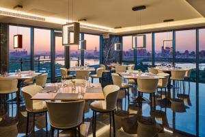 un ristorante con tavoli, sedie e ampie finestre di Suz & Catorze Taipei, a Tribute Portfolio Hotel a Taipei