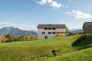une maison sur une colline avec un champ vert dans l'établissement NEU Uuszit985 - auszeit mit ausblick, à Schwarzenberg im Bregenzerwald