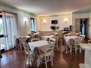 un comedor con mesas y sillas blancas en Hotel La Rama, en Lazise