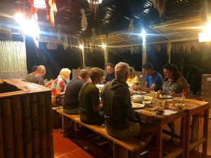 eine Gruppe von Menschen, die an einem Tisch in einem Restaurant sitzen in der Unterkunft Pu Luong Riverside Lodge in Hương Bá Thước