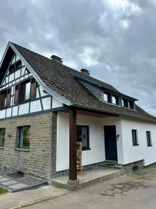 uma casa branca com um telhado preto em Traumfabrik Eifel mit Sauna & Whirlpool em Monschau