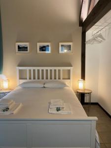 a bedroom with a white bed with three pictures on the wall at Villa Onedo in Abbadia Lariana