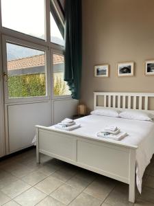 a white bed in a bedroom with a window at Villa Onedo in Abbadia Lariana