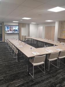 une salle de conférence avec des tables et des chaises et un tableau blanc dans l'établissement Hôtel du Beffroi Gravelines Dunkerque, à Gravelines