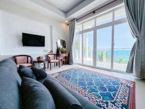 een woonkamer met een grote bank en een groot raam bij Sand Beach Resort in Mũi Né