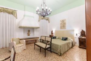 a bedroom with a bed and a chair and a chandelier at Hotel Sant'Antonin in Venice