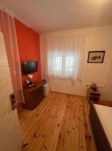 a living room with a wooden floor and a television at Club Themis Hotel in Kotor