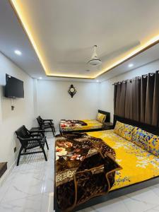 a living room with two beds and a tv at Moven Inn Hotel Islamabad in Islamabad