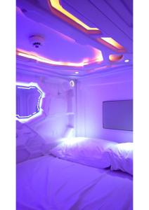 a bedroom with a bed in a room with purple lights at BLR Pods in Bangalore