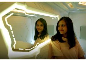 two women sitting on an airplane looking in a mirror at BLR Pods in Bangalore