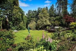 a garden with purple flowers and trees in the background at Heatherlie House in Selkirk