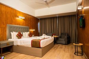a hotel room with a bed and a chair at Hotel Asrani International in Secunderabad