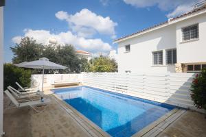una piscina con una sombrilla y una casa en Serifos Villa 7 - 100 meters from Malama Beach, en Protaras