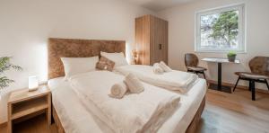 um quarto com 2 camas com lençóis brancos e uma janela em Ferienapartments Tramin Z1 em Termeno