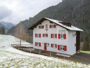 a white building with red shutters in a snow covered field at Urbane Apartment in Sankt Gallenkirch with Balcony in Sankt Gallenkirch