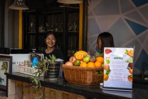 a woman sitting at a counter with a basket of fruit at White Rabbit Hostel in Siem Reap