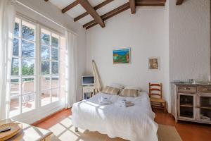 une chambre avec un lit, une table et des fenêtres dans l'établissement Le Mas des Oliviers - Welkeys, à La Croix-Valmer