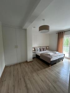 a white bedroom with a bed and a large window at Rezydencja Leśniów in Żarki