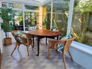 - une table et des chaises en bois sur une terrasse couverte avec moustiquaire dans l'établissement Fernhurst holiday apartments, à Shanklin
