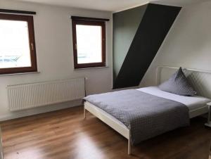 a bedroom with a bed and two windows at Komfortabele Ferienwohnungen mitten im Zentrum Bremerhavens in Bremerhaven