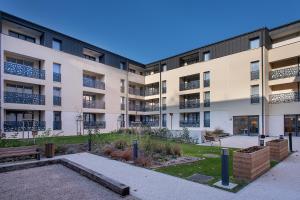 um edifício de apartamentos com um parque em frente em Domitys La Clef des Arts em Châlons-en-Champagne